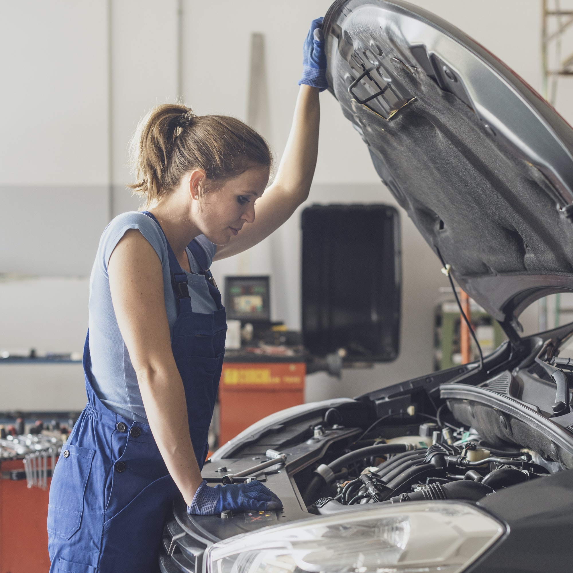 Female mechanic checking a car engine
