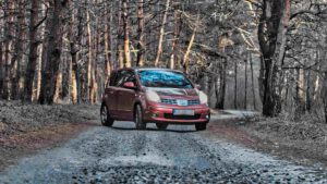 Autopflege im Herbst und Winter: Ein Auto wendet frisch geputzt auf einer winterlichen Waldstraße.