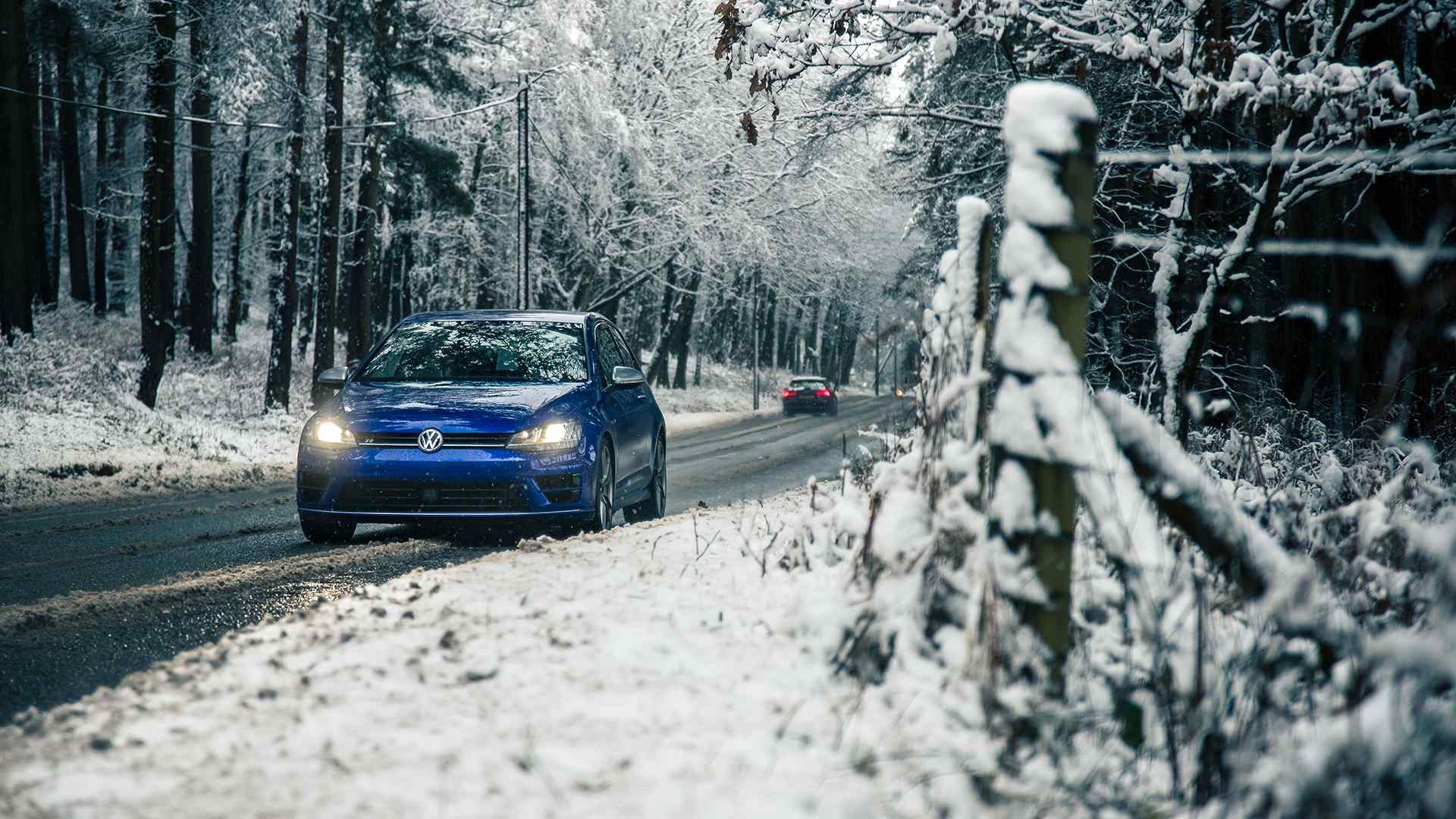 Fahren ohne Winterreifen: Ein Auto mit Winterreifen steht auf einer verschneiten Straße, bereit zum Losfahren.