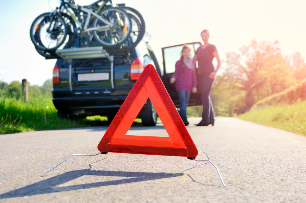 Familie steht vor Pkw nach einem Autounfall im Urlaub