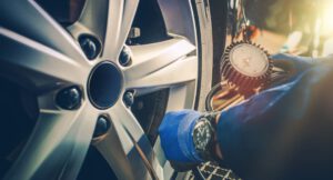 Sommercheck: Ein Mann überprüft bei Sonnenschein den Reifendruck eines Autos