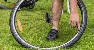 Fahrradreifen wechseln: Eine Person repariert das Vorderrad eines Fahrrads auf einer Grasfläche.